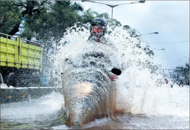  ?? BEAWIHARTA/ REUTERS ?? A man drives a motorcycle through floodwater­s in Jakarta, Indonesia, on Monday. Torrential rains have overwhelme­d city drains and flooded roads and thousands of homes.