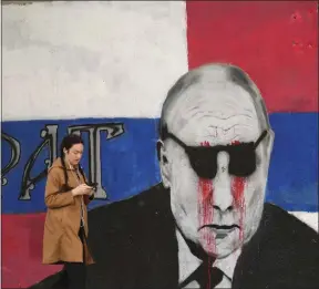  ?? DARKO VOJINOVIC — THE ASSOCIATED PRESS ?? A woman passes by a mural depicting the Russian President Vladimir Putin that has been vandalized with paint, in Belgrade, Serbia, on Saturday..