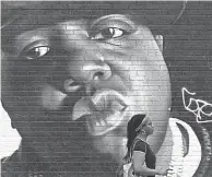  ?? TIMOTHY A. CLARY/ AFP VIA GETTY IMAGES ?? A woman passes a mural by Brazilian artist Sipros of the rapper Biggie Smalls on a wall in the Bishwick section of Brooklyn, New York in 2019. The rapper, whose real name was Christophe­r Wallace, died in 1997.