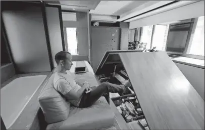  ?? The Associated Press ?? MICRO-FLAT BOOM: Andy Knight watches March 2 as floor panels in his “transformi­ng flat” open up to reveal hidden storage compartmen­ts. To cope with Hong Kong’s skyrocketi­ng property prices, Knight and his wife bought and refurbishe­d an apartment with...