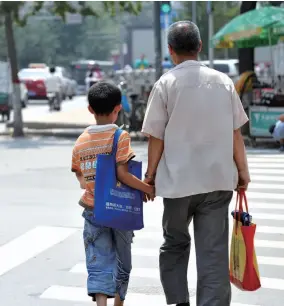 ??  ?? 暑假期间，太原一名家长带着背着­补习班材料的孩子顶着­烈日走在路上