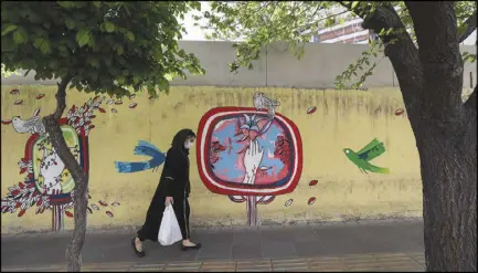  ??  ?? إيرانية تمرّ بجدارية في أحد شوارع العاصمة طهران أمس
