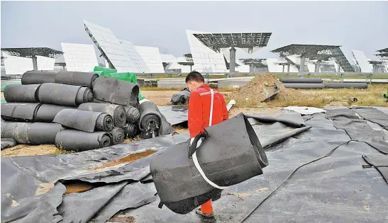  ?? G. BAKER/AFP ?? Un trabajador lleva material aislante en la Base de Generación de Energía Solar Térmica Yanqing, al norte de Pekín.