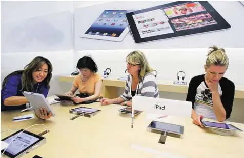  ??  ?? Fight for dominance hots up An Apple worker (left) gives a tutorial on the iPad to customers at an Apple store in Palo Alto, California. Apple wants to make permanent a preliminar­y ban it won on US sales of a Samsung tablet, and extend the ban to...