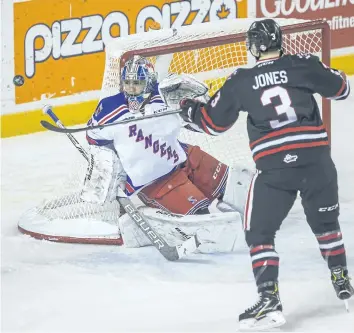  ?? PHOTOS BY BOB TYMCZYSZYN/ STANDARD STAFF ?? Kitchener Rangers goalie Mario Culina has his eye on the puck as Niagara IceDogs Ben Jones ( 3) tries to tip in a loose puck in OHL action Wednesday at Meridian Centre in St. Catharines.