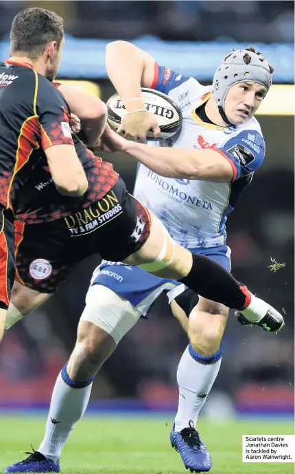  ??  ?? Scarlets centre Jonathan Davies is tackled by Aaron Wainwright.