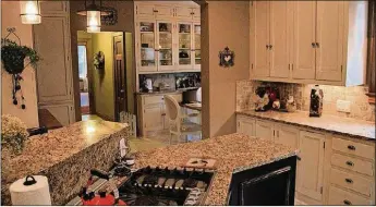  ??  ?? Creative renovation of the kitchen makes use of period cabinets rising to the ceiling and large windows with refinished wood casings and sills. Granite counters, large ceramic tile flooring and high-end appliances have been added.