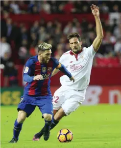  ?? — AP ?? SEVILLE: Barcelona’s Messi, left, challenges for the ball with Sevilla’s Mudo Vazquez during their La Liga soccer match between Sevilla and Barcelona at the Sanchez Pizjuan stadium, in Seville, Spain on Sunday.