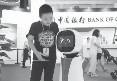  ?? A JING / FOR CHINA DAILY ?? A child interacts with Bank of China's robot receptioni­st during the 25th China Internatio­nal Financial Exhibition in Beijing.