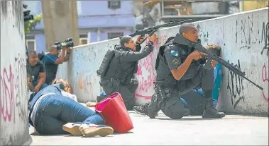  ?? FOTOS: AFP ?? CUERPO A TIERRA. Una vecina de la Rocinha se protege de un tiroteo entre soldados y traficante­s.