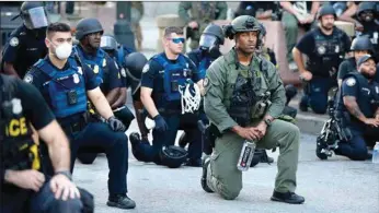  ??  ?? Officers kneel with protesters during a protest against the death in Minneapoli­s of George Floyd, in downtown Atlanta, Georgia