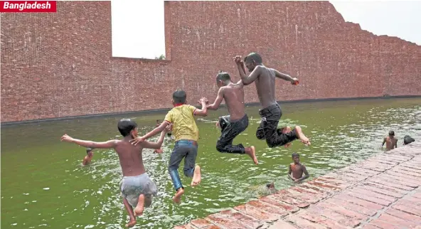  ?? — Reuters ?? Cool respite: Children jumping into the water body of Martyred Intellectu­als Memorial at Rayerbazar, to cool themselves during a heatwave in Dhaka.