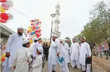  ?? AP ?? Muslims share Eid greeting after offering Eid Al Fitr prayers in Karachi yesterday.
