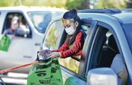  ?? Photos by Robin Jerstad / Contributo­r ?? Lisa Garza looks over treats she got during a 2020 Halloween drive-thru event at Pearsall Park. Coronaviru­s concerns have canceled some holiday events this year.