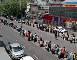  ?? ANI ?? People stand in long queues outside the New Delhi Railway Station to travel by trains to reach their native places on Tuesday. Three special trains started from Delhi for various destinatio­ns. —