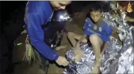  ?? ROYAL THAI NAVY FACEBOOK PAGE VIA AP ?? In this image taken from video provided by the Royal Thai Navy Facebook Page, a Thai Navy SEAL medic helps an injured child inside a cave in Mae Sai, northern Thailand. The Thai soccer teammates stranded more than a week in the partly flooded cave said they were healthy on a video released Wednesday, as heavy rains forecast for later this week could complicate plans to safely extract them.