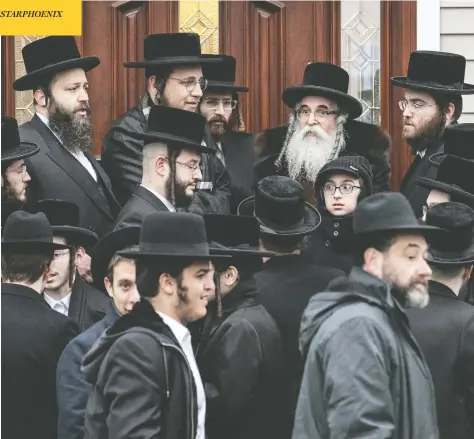  ?? JEENAH MOON / REUTERS ?? Rabbi Chaim Rottenberg and others gather outside his home in Monsey, N.Y., where an attacker burst in Saturday evening and stabbed five people.