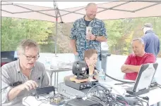  ?? Keith Bryant/The Weekly Vista ?? Bella Vista Radio Club technical officer Steve Warner, left, operates a radio unit while Scout Luke Kessler talks into the handset. Radio club member Will Kessler watches his son handle the radio alongside fellow club member Frank Majdan.