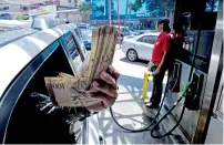  ?? — AFP ?? A customer shows Bolivar bills at a gas station in Caracas.