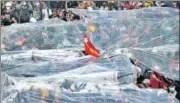  ??  ?? Protesters hold up plastic sheets to protect themselves from a possible firing of water cannons in Yangon on Tuesday.