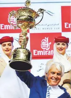  ?? Ahmed Ramzan/Gulf News ?? Trainer Bob Baffert lift the World Cup trophy after Arrogate, ridden by 51-year-old Mike Smith, won the Dubai World Cup at Meydan on Saturday.