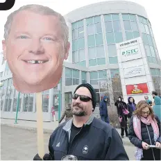  ?? MICHAEL BELL ?? Curt Woytiuk, a member of SGEU, holds a Brad Wall sign at a rally against the plan to shut down the Saskatchew­an Transporta­tion Company. Wall is dealing with a lot of criticism over his government’s decisions.