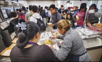  ?? ASSOCIATED PRESS ?? Cafeteria workers serve student lunches last week at Firebaugh High School in Lynwood. Demand for school lunches has increased after California guaranteed free meals to all students regardless of their family’s income.