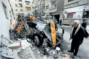  ?? LOUAI BESHARA/ GETTY IMAGES ?? A man looks at damaged vehicles in a street that was reportedly struck by mortar shrapnel from rebel bombardmen­t the previous day in Jaramana, southeast of the Syrian capital Damascus, on Monday.