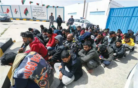  ?? AFP ?? Libyan security forces accompany migrants whose boat was intercepte­d off the coast trying to illegally sail the Mediterran­ean, into a reception center near Tripoli.