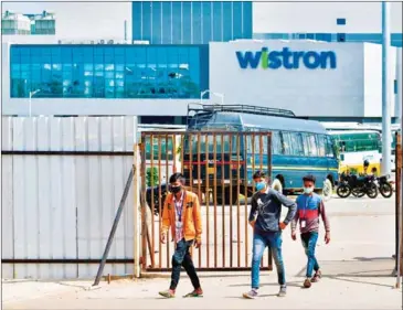  ?? AFP ?? People exit from the gate of Wistron, a Taiwanese-run iPhone factory at Narsapura, about 60km from Bangalore, India, on Sunday.