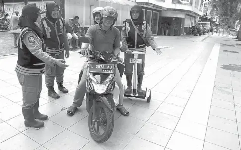  ?? DITE SURENDRA/JAWA POS ?? SALAH JALAN PAK..: Petugas satpol PP mengingatk­an pengendara sepeda motor untuk tidak melintas di trotoar Jalan Urip Sumoharjo.