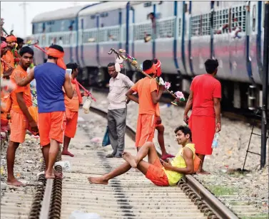  ?? AFP ?? A devotee of Lord Shiva, kanwariya, sits on the railway track at Daraganj railway station as they arrive to collect water from the river Ganga for their ritualisti­c walk towards Varanasi during the holy month of Shravan, in Allahabad, on Wednesday.