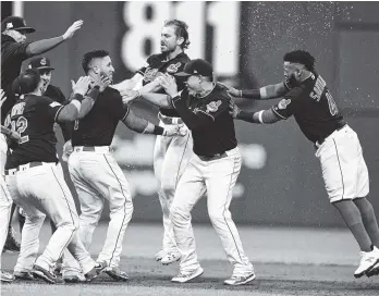  ?? THE ASSOCIATED PRESS ?? Cleveland’s Yan Gomes, center, is mobbed by teammates after the Indians defeated the New York Yankees 9-8 in 13 innings in Game 2 of their American League Division Series on Friday night in Cleveland.