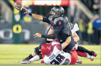  ?? Jonathan Ferrey Getty Images ?? ARIZONA’S Jared Tevis tackles Oregon quarterbac­k Marcus Mariota as he tries to pitch the ball Thursday night. TheWildcat­s sacked Mariota five times in a 31- 24 victory over the No. 2 Ducks.