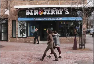  ?? CHARLES KRUPA — THE ASSOCIATED PRESS ?? Pedestrian­s walk on Church Street past the Ben & Jerry's shop in Burlington, Vt., in 2020. Unilever, the company that makes Ben & Jerry's ice cream, said Tuesday it is cutting 7,500jobs and spinning off its ice cream business.