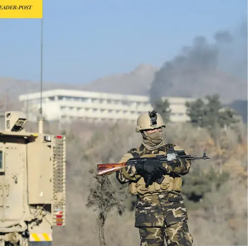  ?? WAKIL KOHSAR / AFP / GETTY IMAGES ?? An Afghan security officer stands guard as black smoke rises from the Interconti­nental Hotel following a weekend attack in Kabul.