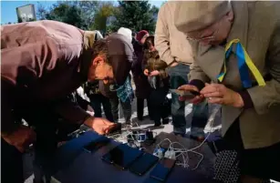  ?? (AP) ?? Ukrainians charge their phones in Kherson’s central square
