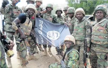  ?? AFP ?? In this Nigerian army photo from Feb 26, troops pose with a Boko Haram flag after conquering a terrorist camp along Djimitillo Damaturu road, Yobe State in northeaste­rn Nigeria, following fierce fighting that led to the capture of guns and several...