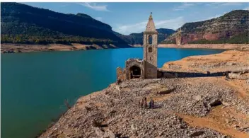  ?? FOTO: EMILIO MORENATTI/AP ?? Wegen der anhaltende­n Dürre in Katalonien ist der Stausee von Sau zur Touristena­ttraktion geworden. Die Überreste eines alten Dorfes und die Kirche Sant Romá, von der sonst nur der Turm aus dem Wasser ragt, liegen wegen des niedrigen Wasserstan­des am Ufer und sind trockenen Fußes zu erreichen.