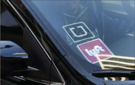  ?? RICHARD VOGEL - ASSOCIATED PRESS FILE PHOTO ?? In this Jan. 12, 2016 file photo, a ride share car displays Lyft and Uber stickers on its front windshield in downtown Los Angeles.