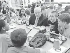  ?? CAROLYN KASTER, AP ?? Agricultur­e Secretary Sonny Perdue has lunch with students in a cafeteria at Catoctin Elementary School in Leesburg, Va., on Monday after he unveiled a rule on school lunches.