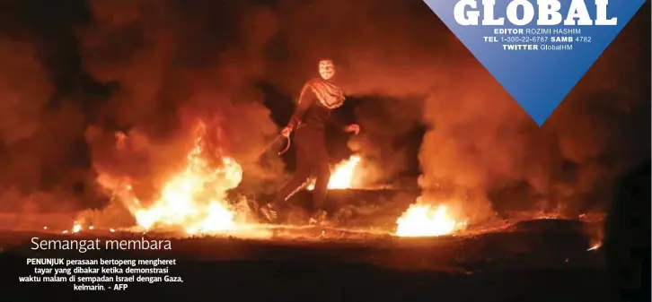  ??  ?? PENUNJUK perasaan bertopeng mengheret
tayar yang dibakar ketika demonstras­i waktu malam di sempadan Israel dengan Gaza,
kelmarin. - AFP