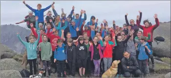  ??  ?? The 37 S1 pupils, teachers, outdoor instructor­s and canine friends celebrate reaching the summit of Goatfell.