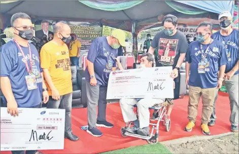  ?? ?? Bung Moktar (centre) presents a mock cheque to a former football player, Mahmood kalong, during the launch of BMR Cup under-18 tournament at Likas Sports Complex on Saturday.
