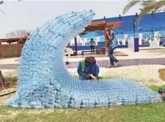  ?? Abdul Rahman/Gulf News ?? A worker prepares an installati­on crafted out of water bottles at the World of Water pavilion during a media tour of the Mother of the Nation Festival at Abu Dhabi Corniche.