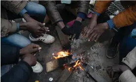  ?? ?? Sudanese migrants warm their hands in a makeshift camp between Calais and Dunkirk, waiting to cross the English Channel via small boats.