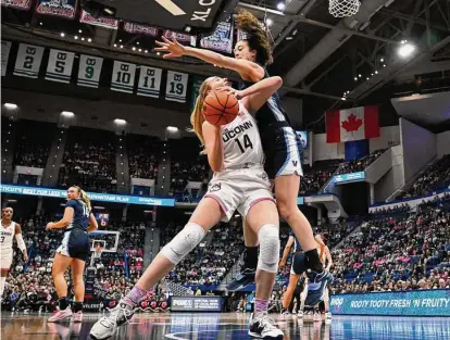  ?? Jessica Hill / Associated Press ?? UConn’s Dorka Juhasz, left, is pressured by Villanova’s Maddy Siegrist in the first half on Sunday in Hartford.