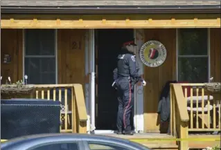  ?? PHOTOS BY JOHN RENNISON, THE HAMILTON SPECTATOR ?? A police officer on the porch of 21 Holly Ave. A neighbour says the resident was shot in the torso and hand.