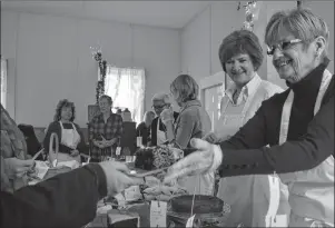  ?? NIKKI SULLIVAN/CAPE BRETON POST ?? Aggie MacMillan, right, hands someone some homemade chocolate cake while Anna Travis smiles beside her. The two were volunteeri­ng for the annual Dessert Social fundraiser for the Coxheath Hills Wilderness Recreation Associatio­n on Sunday.