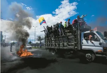  ?? DOLORES OCHOA/AP ?? Anti-government protesters ride past a burning barricade during demonstrat­ions Thursday in Quito, Ecuador. An Indigenous group called for protests to demand a reduction in the price of gasoline, a moratorium on the extension of mining and oil projects and the setting of a minimum price for agricultur­al products. The group’s leader was arrested Tuesday.